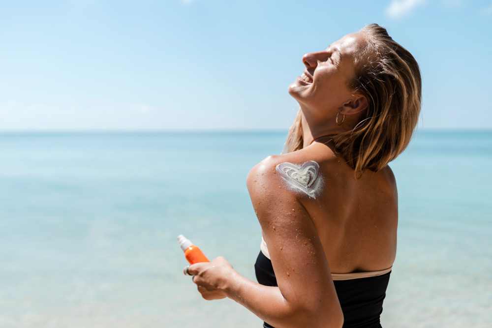 Vitamin D u moře a žena, která se maže opalovacím krémem 